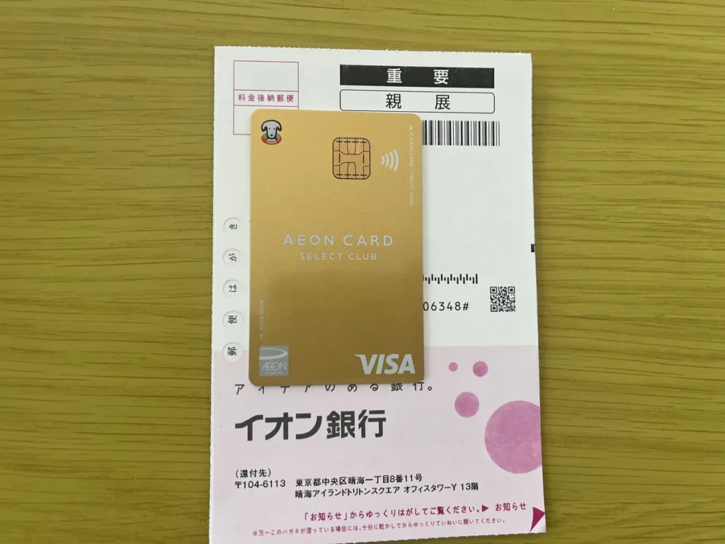 イオン銀行からの郵便物の上に置かれた金色のAEON CARD SELECT CLUB。