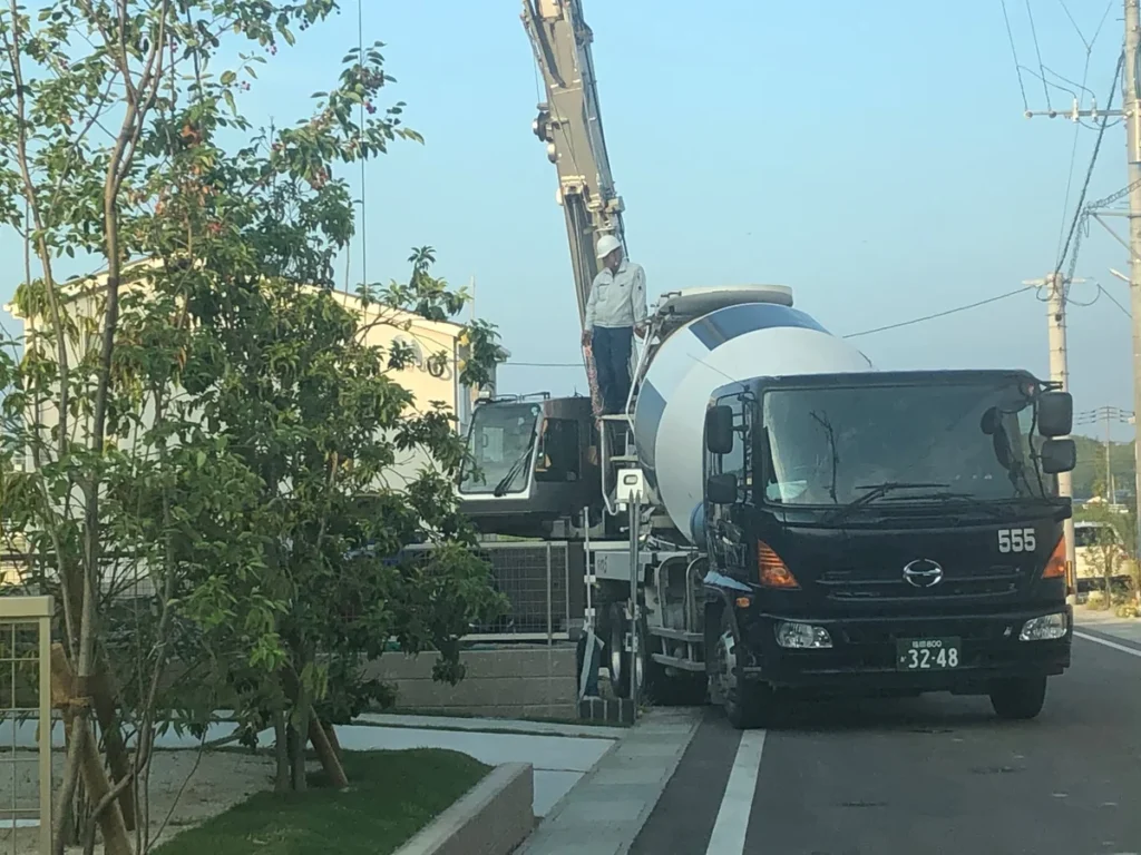 基礎工事現場に停車したコンクリートミキサー車とクレーン