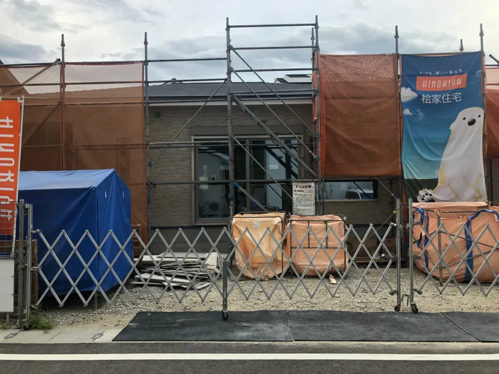 外壁と屋根が仕上がり足場が残る建築中の平屋住宅正面