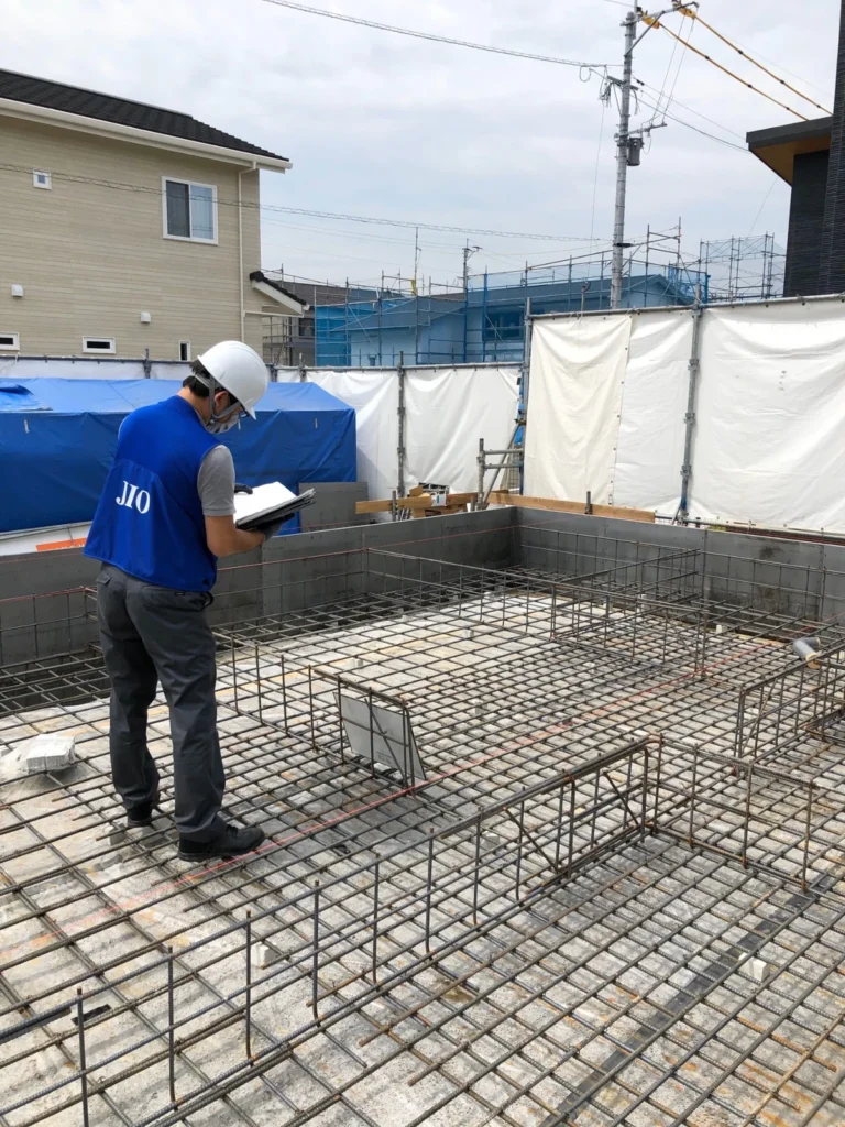 住宅基礎の配筋全体を、担当者が現場で図面と照合している