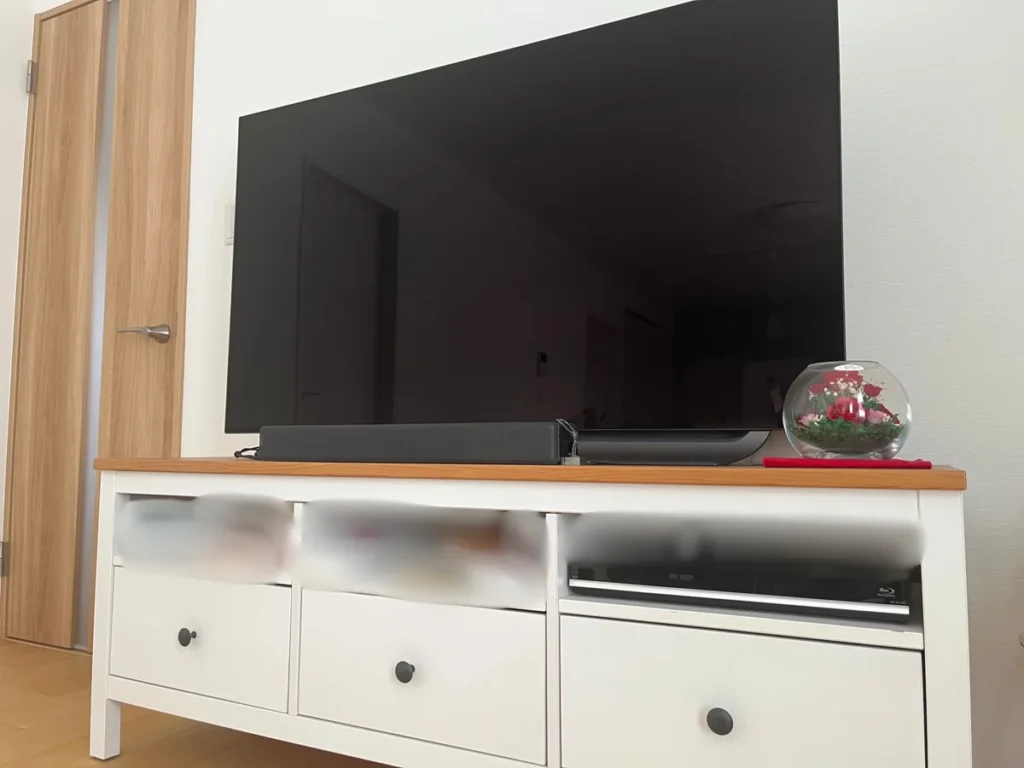 白いテレビ台の上に置かれた大型テレビとサウンドバー