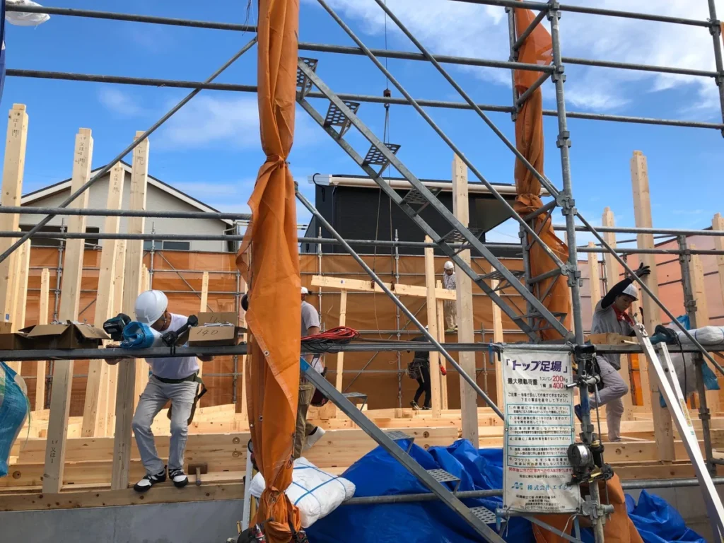 木造住宅の柱と梁を組み立てる作業員たち