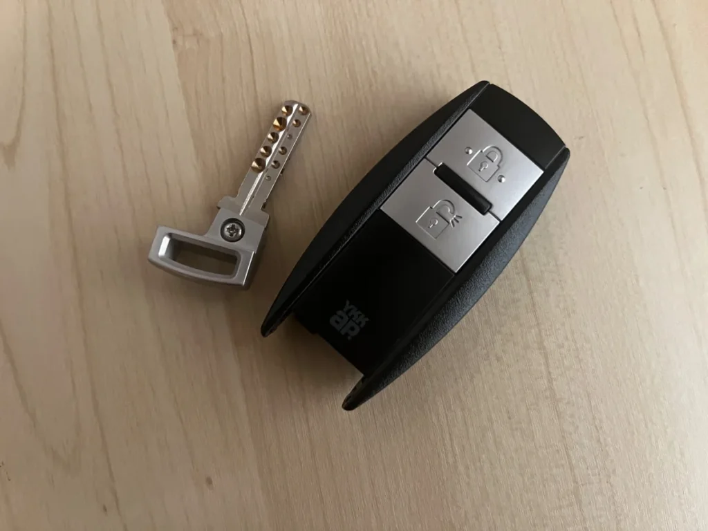 木目のテーブルに並べたYKK APのスマートキーと収納式の非常用鍵