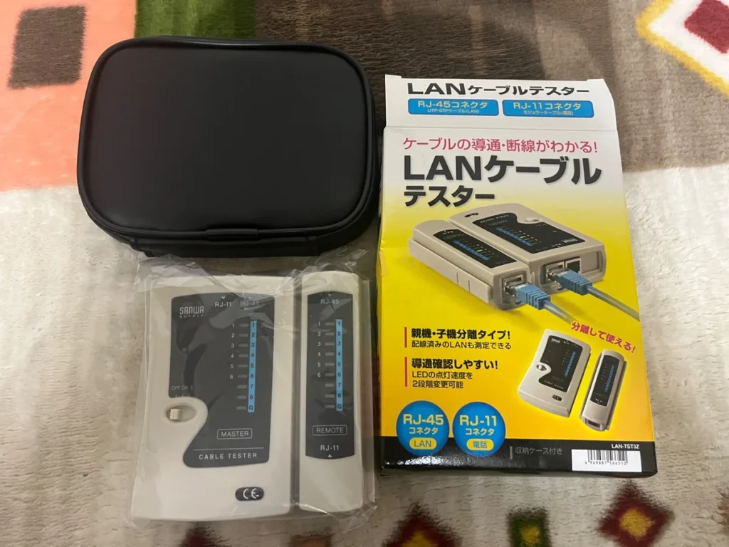 LANケーブルテスター本体、子機、収納ケース、パッケージを並べた様子