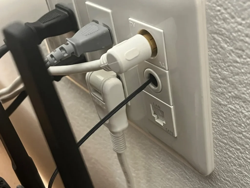 テレビ端子や電源プラグが接続され、下部にCAT6のLAN端子がある壁面コンセント
