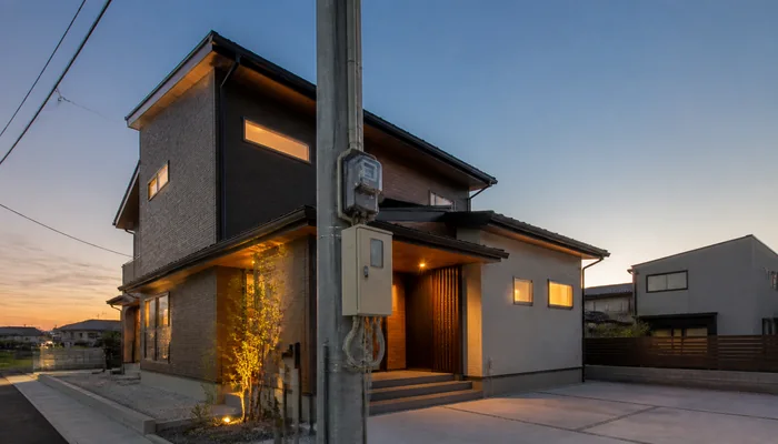 夕暮れに明かりがともる新築住宅と電気メーター
