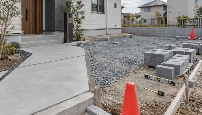 コンクリート通路と砕石下地、施工前のブロックが並ぶ新築外構工事の途中