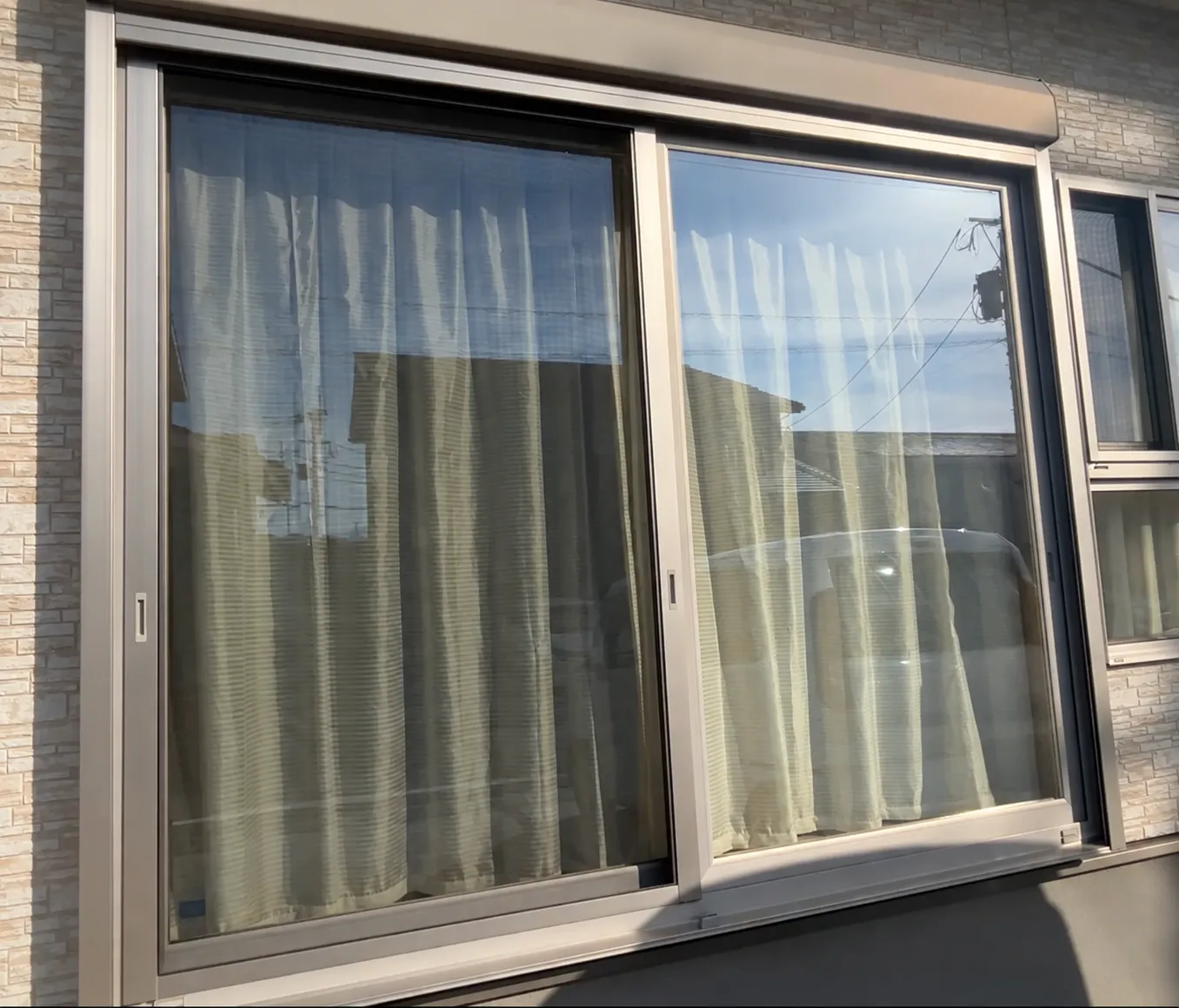 屋外から正面方向に見た大きな2枚建て引き違い窓。上にシャッターボックスが付いている