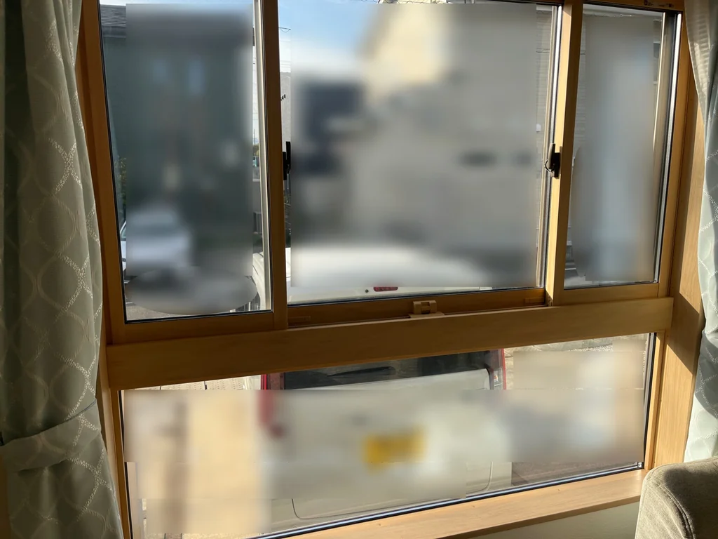 室内側から見たリビングのデザイン窓。上部の窓と下段の横長FIX窓、カーテンが写っている