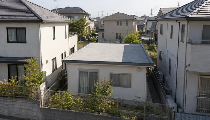 二階建ての隣家に挟まれた平屋に、建物の影が差している