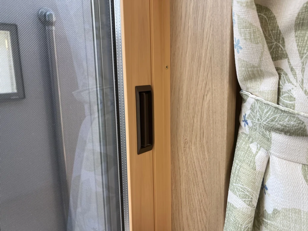 木目調の引き違い窓に付いたYKK APの戸先錠を閉じた状態で写した写真