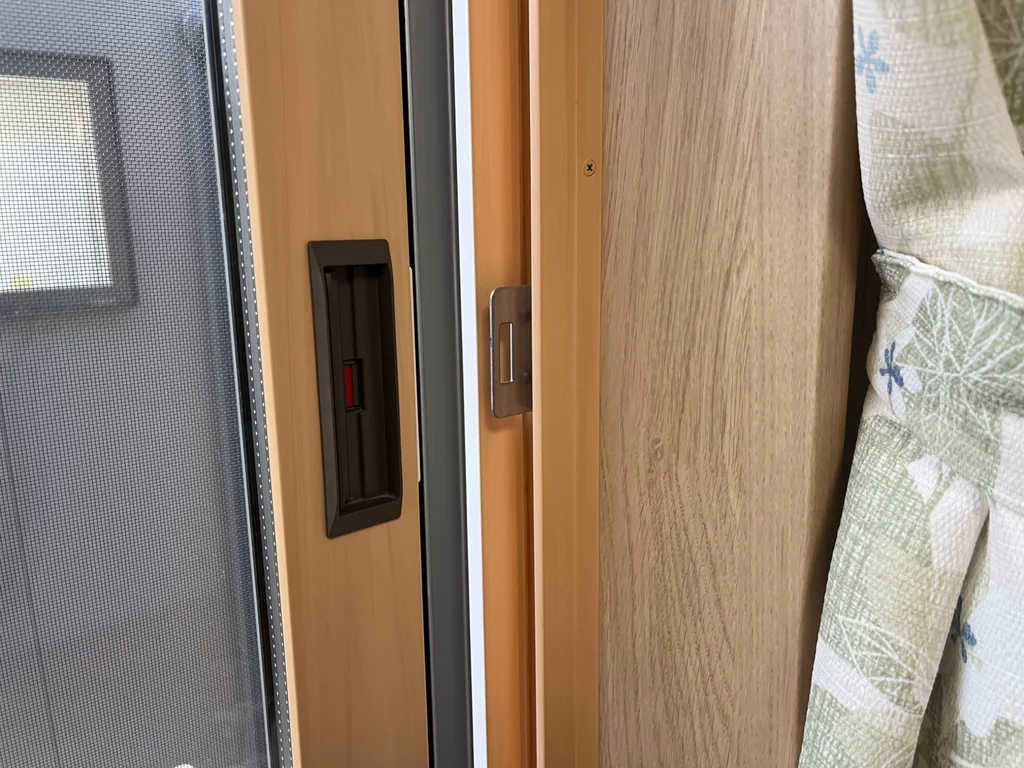 木目調の引き違い窓に付いたYKK APの戸先錠を開いた状態で写した写真