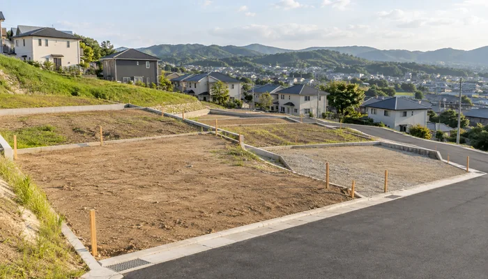 造成地に境界杭で区切られた複数の住宅用区画が斜面に沿って並んでいる